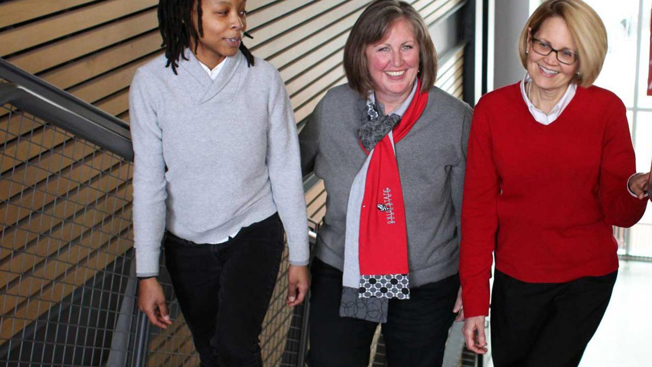 three smiling women walking up a stair well